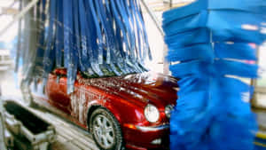 紅色汽車在自動洗車機中被藍色刷子清潔。