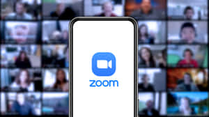 智能手機顯示 Zoom 應用程式標誌，背景為模糊的視像通話網格。