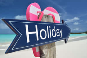 藍色箭頭標誌 Holiday 文字及粉紅色人字拖在海灘上