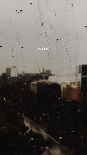 窗戶上的雨滴，模糊的城市景觀和 /wait/ 文字。