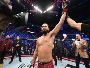 UFC拳手在八角籠中由裁判舉手慶祝勝利。