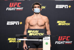 UFC拳手在稱重時站在體重磅上，戴著口罩