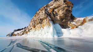 在清澈的藍天下，冰凍的湖泊上有冰層和積雪覆蓋的岩石。