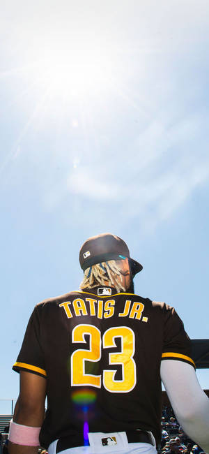 身穿黑色和黃色球衣的棒球手Tatis Jr站在燦爛陽光下。