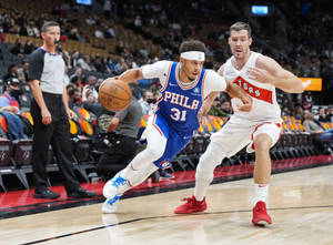費城76人隊球員在NBA比賽中運球越過多倫多速龍隊防守球員。