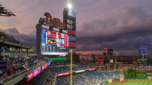 黃昏時分人群擠滿的棒球場，配有巨型記分板和 Phillies 標誌。 — 費城老鷹 壁紙