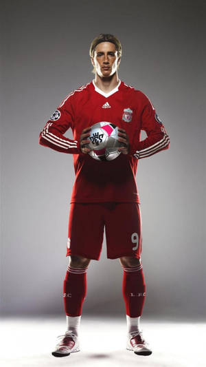 身穿紅色利物浦球衣的足球員在攝影棚中手持足球。