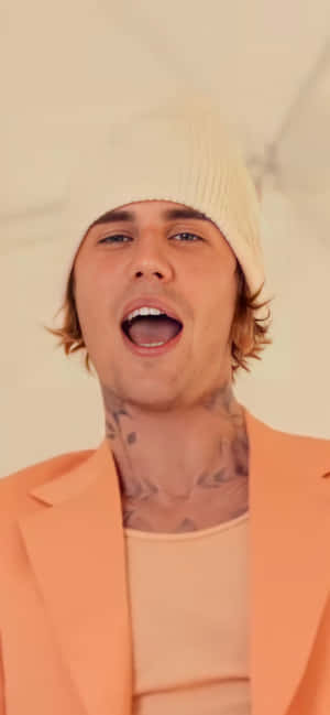 Justin Bieber 穿著桃紅色西裝外套和奶油色無邊帽演唱。 — Pixel 8a 壁紙