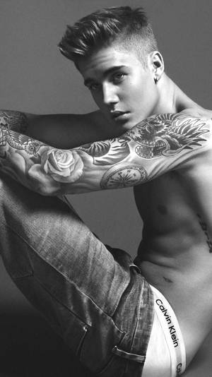 有紋身的年輕男子穿著牛仔褲和Calvin Klein內褲擺姿勢。