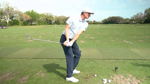男子在陽光明媚的綠色球場上揮動高爾夫球桿