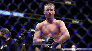 一名戴著手套的男性MMA拳手在比賽後站在UFC八角籠內。