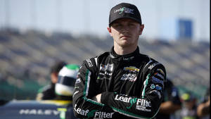 NASCAR車手穿著賽車裝備在賽道上交叉雙臂站立。 — 賽車 壁紙