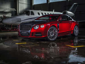 紅色Mansory Bentley跑車停在潮濕機庫中的私人飛機旁。