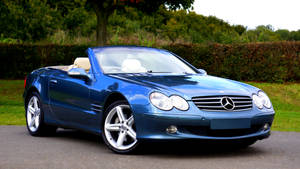 藍色 Mercedes 開篷跑車停泊在帶有綠色樹籬的道路上。