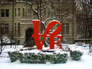 冬季校園環境中，被雪覆蓋的紅色LOVE雕塑。