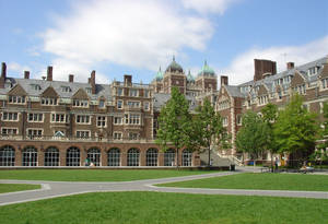 大學校園，擁有歷史磚砌建築和綠色草坪，在藍天下。