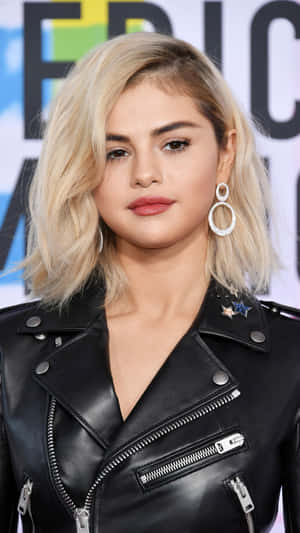 Selena Gomez 穿著帶有星星補丁的黑色皮夾克和大圈耳環。