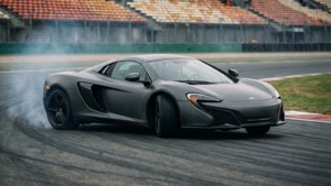 啞光灰色McLaren跑車在賽道上飄移，輪胎冒煙。