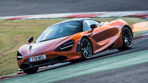橙色McLaren 720S在賽道上疾馳，帶有動態模糊效果。 — 橙色美學 壁紙