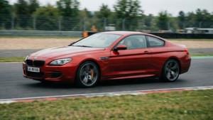 紅色BMW M6雙門跑車在賽道上疾馳，背景模糊。