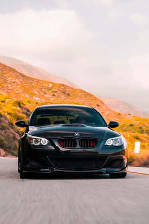 黑色BMW M3在夕陽下的山路疾馳