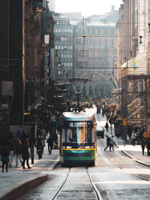 金色夕陽下，綠色電車穿過擁擠的城市街道。