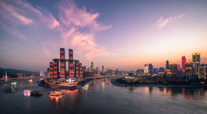 夕陽時分的城市天際線，閃爍的建築物和河流上的船隻。 — 唐人街 GIF 壁紙