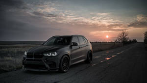 夕陽下潮濕鄉村道路上的啞光黑色BMW X5 M