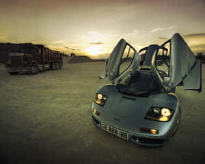 銀色McLaren F1打開鷗翼車門，在沙漠日落時分停泊在一輛紅色自卸卡車旁。