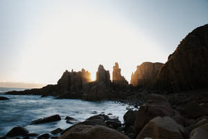 夕陽映照在岩石懸崖後方，溫柔的海浪拍打著海岸 — 風景動圖 壁紙