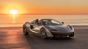 銀色McLaren跑車在日落時停泊在海邊