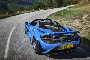 藍色McLaren 570S Spider在日落時分於山路上疾馳。