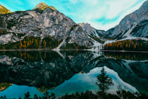 高山湖泊映照山脈和秋天的樹木，天空湛藍