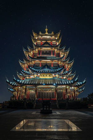 星空下被照亮的傳統寶塔，前景有倒影池