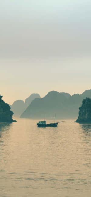 一艘小船漂浮在平靜的水面上，背景是霧濛濛的喀斯特島嶼。