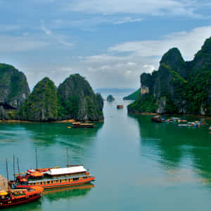 傳統船隻漂浮在碧綠的海灣中，周圍是高聳的綠色石灰岩懸崖。