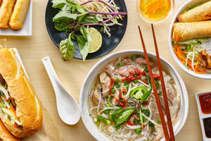 越南菜餚，河粉、春卷和越南法包在木桌上。