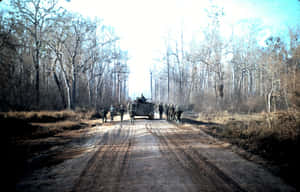 士兵們在泥濘的森林小徑上走在軍用卡車旁邊。
