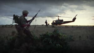 士兵持步槍穿過田野，一架直升機在風暴暮色天空下盤旋。