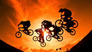 BMX車手在半空中，背景是鮮豔的橙色日落天空。