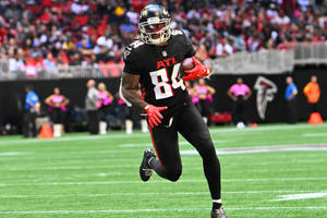 美式足球員在比賽中帶球在球場上奔跑。