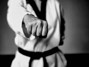 一位身穿白色道服、繫著黑色腰帶的武術家發出強力一拳。 — 黑白 壁紙