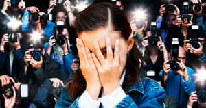 女子在記者人群中遮臉躲避閃光燈。
