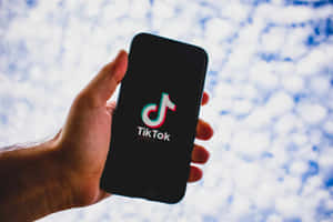 手拿著帶有TikTok標誌的手機，背景是陰天 — TikTok GIF 壁紙