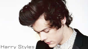 Harry Styles 身穿黑色西裝外套和圖案襯衫，捲髮向下看。