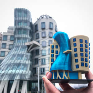 手拿著3D打印的跳舞屋模型，放在真實建築前。