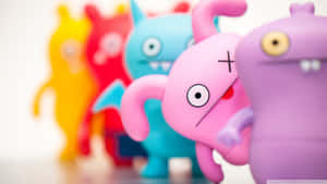 一排彩色Uglydoll玩具，淺景深聚焦在粉紅色上。