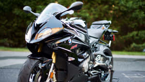 黑色BMW R1200RR運動電單車停泊在瀝青路上，背景有綠色樹木。