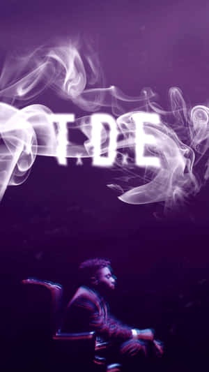 男人坐在椅子上，下方有發光的煙霧字母 T.D.E，在紫色迷霧中。