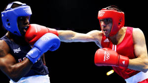 兩名身穿紅色和藍色裝備的男性拳擊手在奧運比賽中互相出拳。